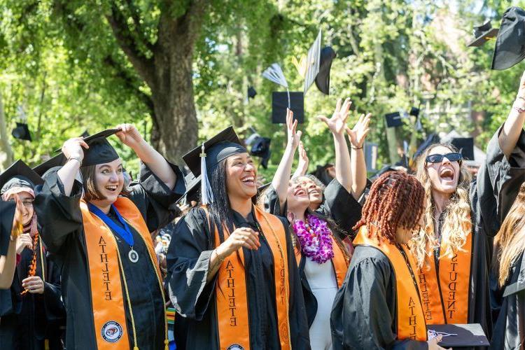 student-athletes throw their graduation caps into the air at commencement